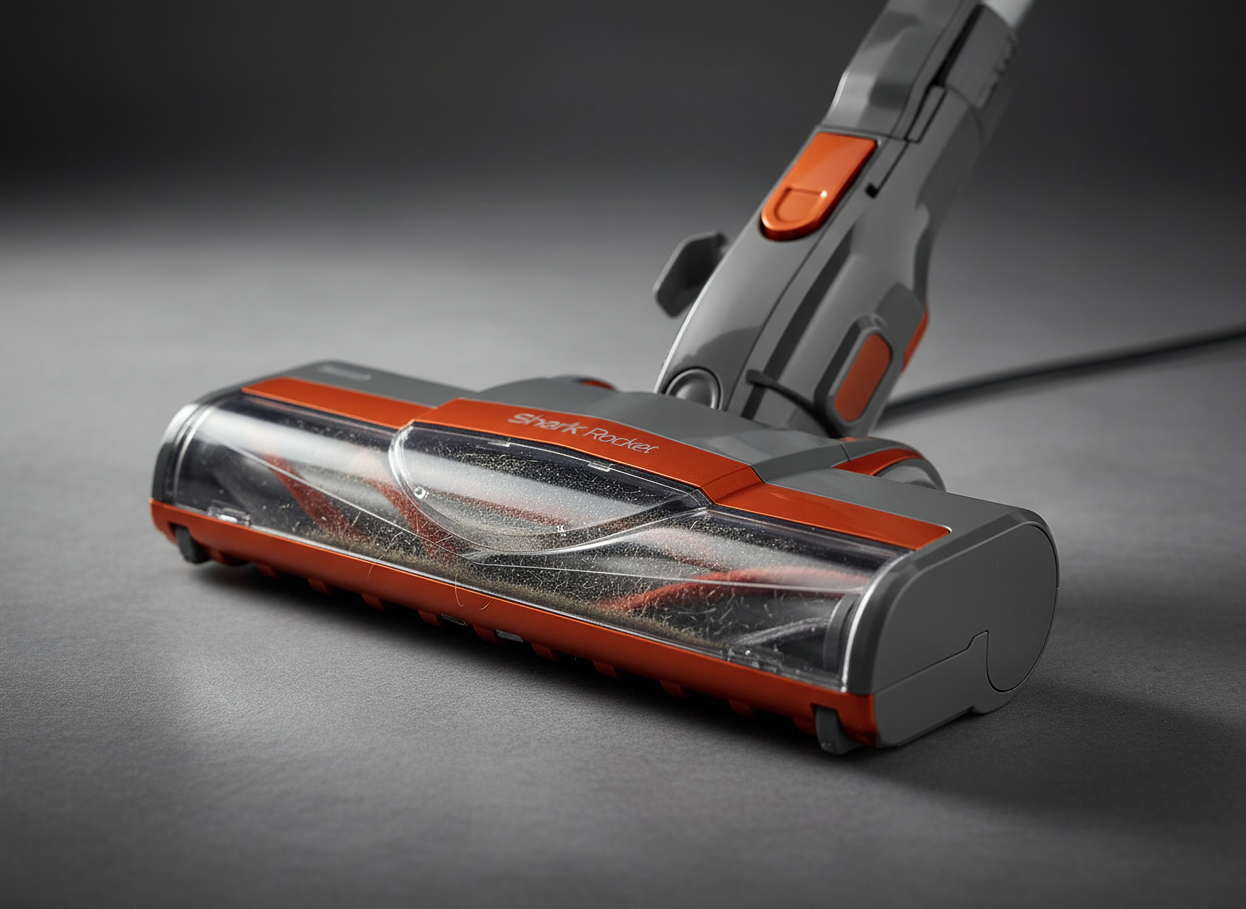 Macro detail of Shark Rocket vacuum brush roll and motor head with orange trim, extreme close-up